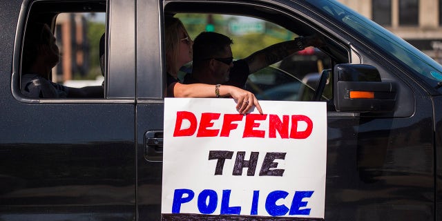 A protester holds a sign that says "Defend the Police" as pro-police protesters pass through downtown Bloomington, Indiana, during a "Defend the Police" event in support of the police and to protest against defunding the police Aug. 8, 2020.