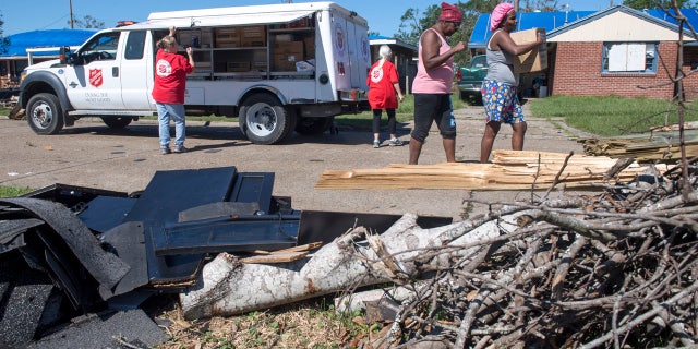 Tavita Carrier and her sister, Vancella Sennett, walk past Hurricane Laura debris piled up and down their street in Lake Charles, La., the morning after Hurricane Delta on Saturday, Oct. 10, 2020.