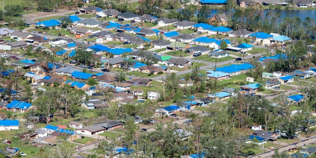 Blue tarps cover houses in the aftermath of Hurricane Delta, Saturday, Oct. 10, 2020, in Iowa, La.