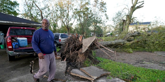 Marcus Peterson walks past a downed tree in his yard after Hurricane Delta moved through, Saturday, Oct. 10, 2020, in Jennings, La.