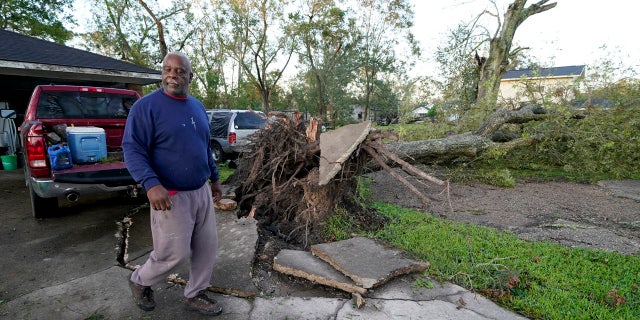Marcus Peterson walks past a downed tree in his yard after Hurricane Delta moved through, Saturday, Oct. 10, 2020, in Jennings, La.