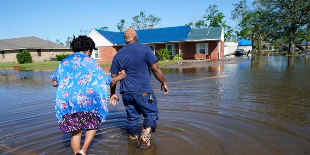 Soncia King holds onto her husband Patrick King in Lake Charles, La., Saturday, Oct. 10, 2020, as they walk through the flooded street to their home, after Hurricane Delta moved through on Friday.