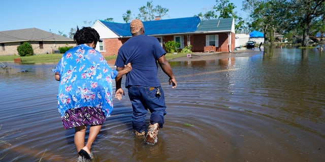 Soncia King holds onto her husband Patrick King in Lake Charles, La., Saturday, Oct. 10, 2020, as they walk through the flooded street to their home, after Hurricane Delta moved through on Friday.
