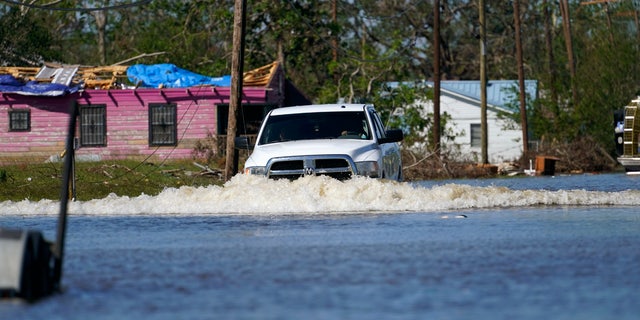 A truck drives through a flooded street in Lake Charles, La., Saturday, Oct. 10, 2020, past a home with damage from Hurricane Laura, after Hurricane Delta moved through on Friday.