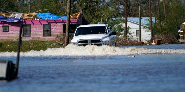 A truck drives through a flooded street in Lake Charles, La., Saturday, Oct. 10, 2020, past a home with damage from Hurricane Laura, after Hurricane Delta moved through on Friday.
