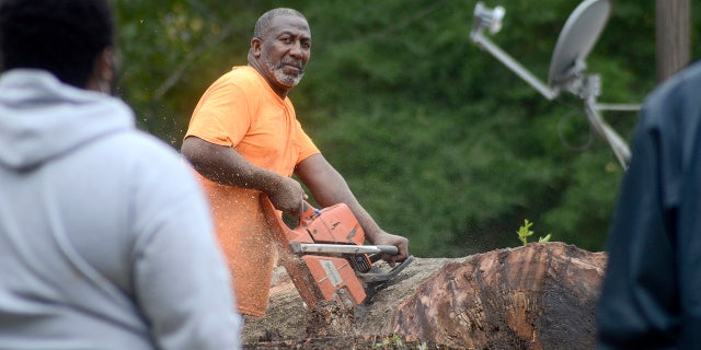 Carey Blackmon cuts an oak tree after it fell on the home of Larry Veal, Saturday, Oct. 10, 2020, in Gloster, Miss., during Hurricane Delta.