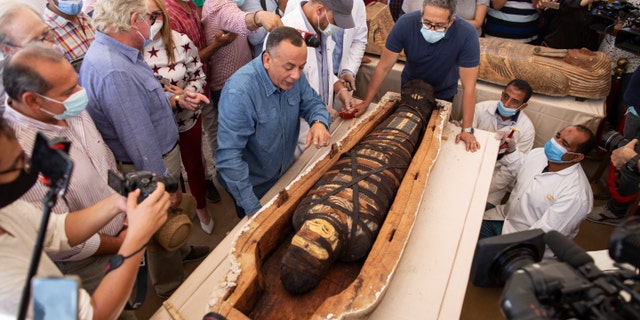 Khalid el-Anany, Egypt's tourism and antiquities minister, right, and Mostafa Waziri, secretary-general of the country's Supreme Council of Antiquities, left, stand over a sarcophagus at the Saqqara archaeological site, 19 miles south of Cairo, Egypt on Saturday, Oct. 3, 2020.