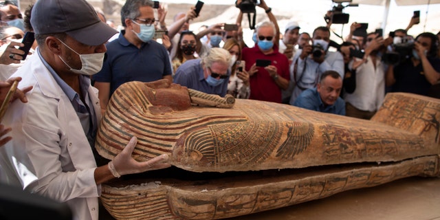 An archaeology worker opens a sarcophagus at the Saqqara archaeological site, 30 kilometers 19 miles south of Cairo, Egypt, on Saturday, Oct. 3, 2020, in the presence of journalists and officials.