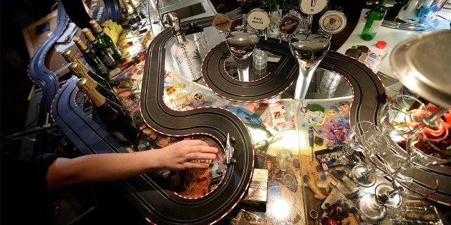 A bartender plays with an electric car track inside a cafe bar, as the Czech government shut all restaurants for two weeks to slow down the spread of COVID-19, in Prague, Czech Republic. (REUTERS/David W Cerny)