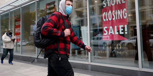 A passer-by walks past a store closing sign, right, in the window of a department store in Boston. Americans may feel whiplashed by a report Thursday, Oct. 29, on the economy's growth this summer, when an explosive rebound followed an epic collapse. The government estimate that the economy grew faster on an annualized basis last quarter than in any such period since record-keeping began in 1947. (AP Photo/Steven Senne)