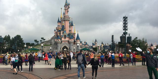 Visitors in protective face masks walk down the Main Street of Disneyland Paris in Marne-la-Vallee, near Paris, on July 15.