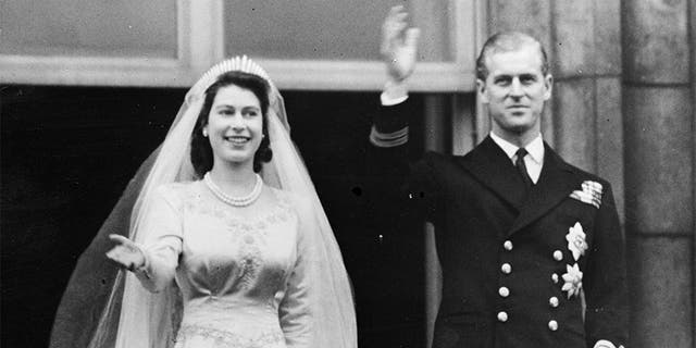  La princesse Elizabeth et le prince Philip, duc d'Édimbourg, saluant une foule depuis le balcon du palais de Buckingham, à Londres, peu de temps après leur mariage à l'abbaye de Westminster en 1947.