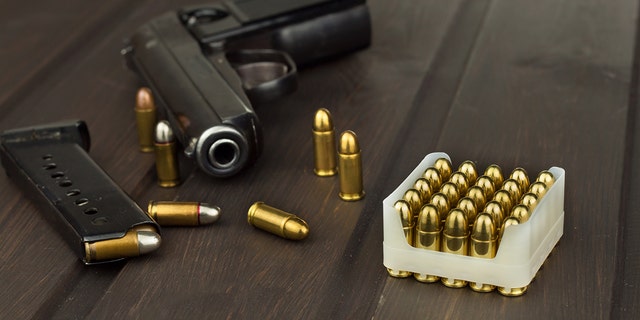 Handgun with ammunition on a dark wooden table.
