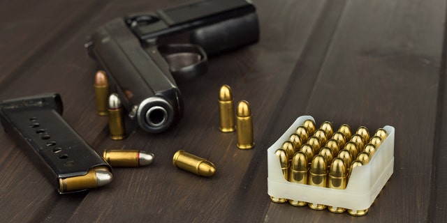 A handgun and bullets on a wooden table