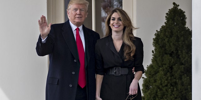 U.S. President Donald Trump waves while standing with Hope Hicks, outgoing White House communications director, right, outside the Oval Office of the White House in Washington, D.C., U.S., on Thursday, March 29, 2018. 