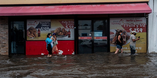 08 October 2020, Mexico, Merida: People walk along a road that was flooded by the heavy rains of hurricane "Delta". "Delta" has gained strength as it heads towards the United States. Photo: Jacky Muniello/dpa (Photo by Jacky Muniello/picture alliance via Getty Images)