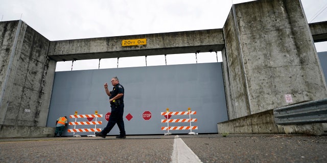 A Plaquemines Parish sheriff deputy walks away after workers closed a floodwall gate on Hwy 39 in Poydras, La., Wednesday, Oct. 28, 2020.