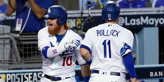 Los Angeles Dodgers' Justin Turner, left, and A.J. Pollock (11) celebrate after Pollock scored on a double by Mookie Betts during the fifth inning in Game 2 of the team's National League wild-card baseball series Thursday, Oct. 1, 2020, in Los Angeles. (AP Photo/Ashley Landis)