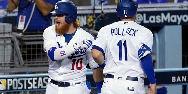 Los Angeles Dodgers' Justin Turner, left, and A.J. Pollock (11) celebrate after Pollock scored on a double by Mookie Betts during the fifth inning in Game 2 of the team's National League wild-card baseball series Thursday, Oct. 1, 2020, in Los Angeles. (AP Photo/Ashley Landis)