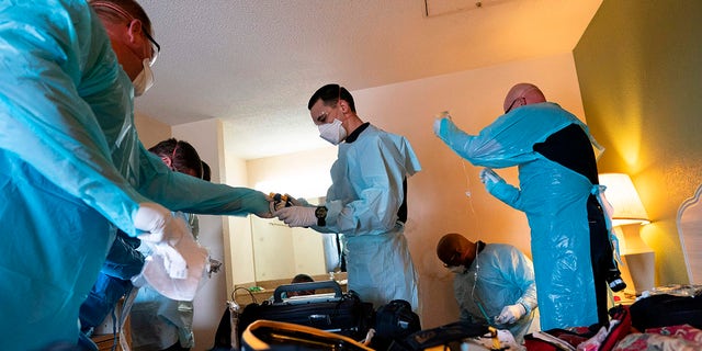 Firefighters and paramedics with Anne Arundel County Fire Department wear enhanced PPE, during the coronavirus pandemic, as they treat a patient in cardiac arrest as a result of a drug overdose. (Photo by ALEX EDELMAN/AFP via Getty Images)