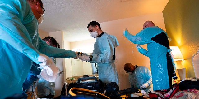 Firefighters and paramedics with Anne Arundel County Fire Department wear enhanced PPE during the coronavirus pandemic as they treat a patient in cardiac arrest as a result of a drug overdose May 6, 2020, in Brooklyn, Maryland. (ALEX EDELMAN/AFP via Getty Images)