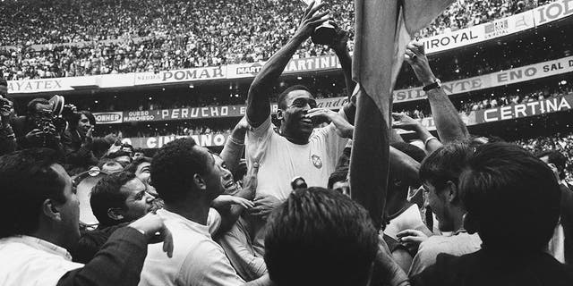 FILE - In this June 21, 1970 file photo, Brazil's Pele holds up his team's Jules Rimet Trophy, or the FIFA World Cup Trophy, following Brazil's 4-1 victory over Italy at the World Cup at the Azteca Stadium in Mexico City. On Oct. 23, 2020, the three-time World Cup winner Pelé turns 80 without a proper celebration amid the COVID-19 pandemic as he quarantines in his mansion in the beachfront city of Guarujá, where he has lived since the start of the pandemic. 