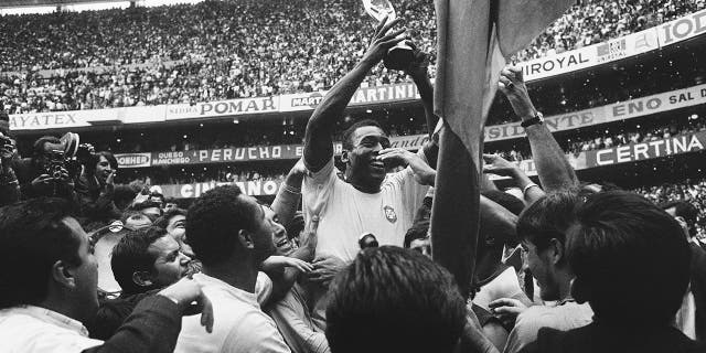 FILE - In this June 21, 1970 file photo, Brazil's Pele holds up his team's Jules Rimet Trophy, or the FIFA World Cup Trophy, following Brazil's 4-1 victory over Italy at the World Cup at the Azteca Stadium in Mexico City. On Oct. 23, 2020, the three-time World Cup winner Pelé turns 80 without a proper celebration amid the COVID-19 pandemic as he quarantines in his mansion in the beachfront city of Guarujá, where he has lived since the start of the pandemic.