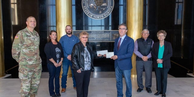 North Dakota Gov. Doug Burgum presents Ron Hepper’s military ID tag to his widow, Ruth Hepper Wednesday at the Capitol in Bismarck. Also pictured are (from left) Maj. Gen. Al Dohrmann, Hepper’s daughter Julie Hornbacher and her husband, Jim, and Ron Hepper’s brother Stanley Hepper and his wife, Kathleen.