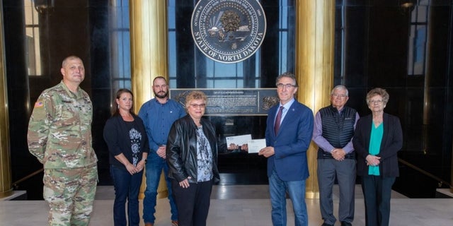 North Dakota Gov. Doug Burgum presents Ron Hepper’s military ID tag to his widow, Ruth Hepper Wednesday at the Capitol in Bismarck. Also pictured are (from left) Maj. Gen. Al Dohrmann, Hepper’s daughter Julie Hornbacher and her husband, Jim, and Ron Hepper’s brother Stanley Hepper and his wife, Kathleen.