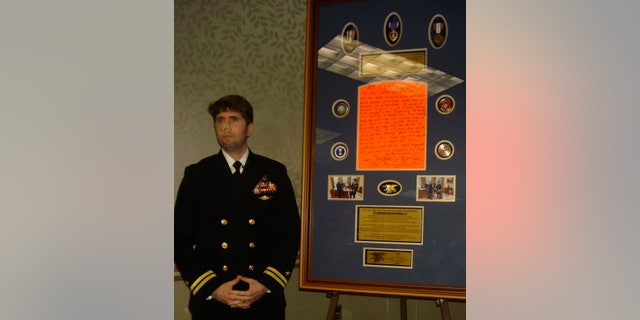 Jason Redman, a former Navy SEAL, stands beside the sign he once placed on his door at Walter Reed.