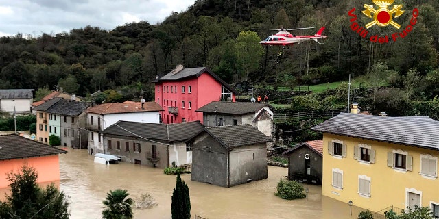 In this image made available Sunday, Oct. 4, 2020, a firefighters' helicopter flies over flooding in the town of Ornavasso, in the northern Italian region of Piedmont.