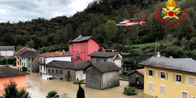 In this image made available Sunday, Oct. 4, 2020, a firefighters' helicopter flies over flooding in the town of Ornavasso, in the northern Italian region of Piedmont.
