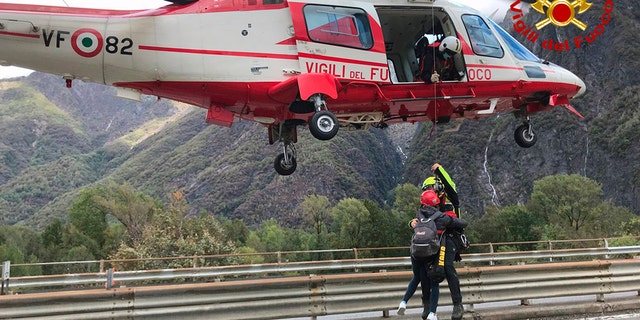 In this image made available Sunday, Oct. 4, 2020, firefighters evacuate people from flooding in the town of Ornavasso, in the northern Italian region of Piedmont. (Firefighter Vigili del Fuoco via AP)