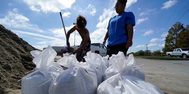 Stephanie Verrett and Jodie Jones fill sandbags to protect their home in anticipation of Hurricane Delta, expected to arrive along the Gulf Coast later this week, in Houma, La., Wednesday, Oct. 7, 2020.