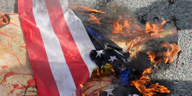 Counter-protesters set fire to a U.S. National flag during a gathering of the far-right group as they hold a protest in Boston, Massachusetts, Oct. 18, 2020.
