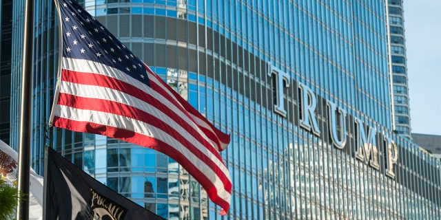 An American flag flying on the Riverwalk at the Vietnam Veterans Fountain late in the day with the Trump Tower.