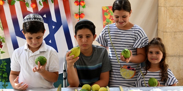 Children celebrate Sukkot at the U.S. Embassy in Jerusalem, Israel, holding up citrons.