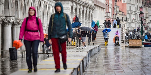 Visitors walk on on a trestle bridges during an expected high water, in Venice, northern Italy, Saturday, Oct. 3, 2020.
