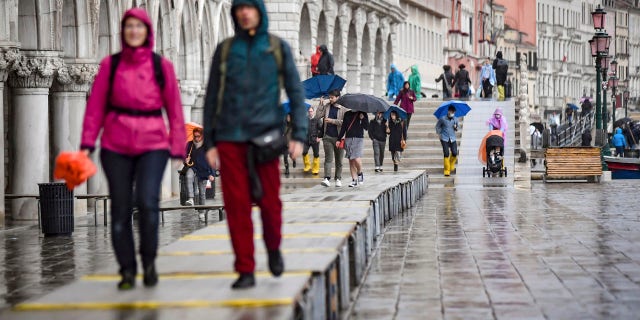 Visitors walk on on a trestle bridges during an expected high water, in Venice, northern Italy, Saturday, Oct. 3, 2020.