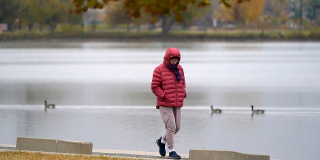 Bundled up against the cold, a man navigates the trail around Sloans Lake after a cold front dropped temperatures Sunday, Oct. 18, 2020, in Denver. (AP Photo/David Zalubowski)