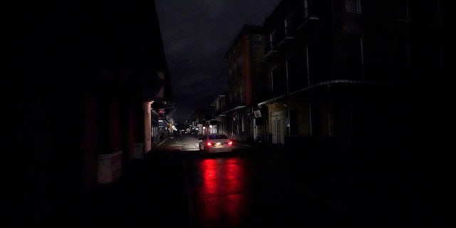 A passing car's headlights illuminate a darkened Bourbon Street in the French Quarter of New Orleans, Wednesday, Oct. 28, 2020.