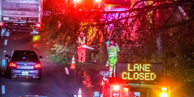 Authorities work to clear a fallen tree that is blocking a lane on I-20 at Langhorn Street in Atlanta on Thursday morning, Oct. 29, 2020. Tropical Storm Zeta sped across the Southeast on Thursday, leaving a trail of damage and more than 2 million homes and businesses in the dark in Atlanta. (John Spink/Atlanta Journal-Constitution via AP)