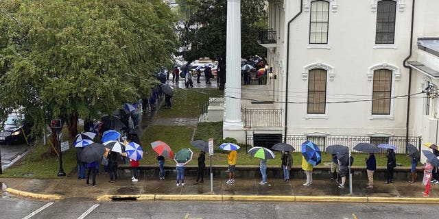 People wait in the rain to vote in Montgomery, Ala., on Saturday, Oct. 24, 2020. Alabama Secretary of State John Merrill said a record number of absentee ballots have already been cast this year in the election. Some counties allowed Saturday voting for the first time. (AP Photo/Kim Chandler)