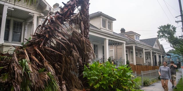 People walk along a sidewalk in New Orleans as the outer eye wall of Hurricane Zeta passed by the city, Wednesday, Oct. 28, 2020. (Chris Granger/The Times-Picayune/The New Orleans Advocate via AP)