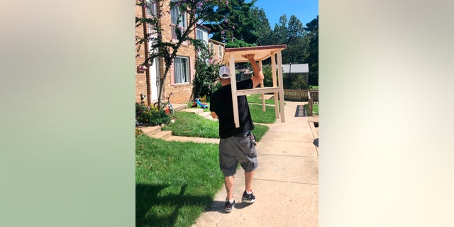 In this photo provided by Jessica Berrellez, her husband, Al Berrellez, carries a desk to a student's home in Gaithersburg, Md., on Sunday, Sept. 13, 2020.