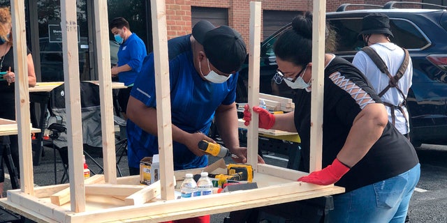 In this photo provided by Jessica Berrellez, volunteers build desks in Gaithersburg, Md. Berrellez and her husband, with the help of some 60 community volunteers, have built and donated over 100 desks to students and families in need.