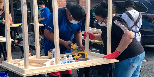 In this photo provided by Jessica Berrellez, volunteers build desks in Gaithersburg, Md. Berrellez and her husband, with the help of some 60 community volunteers, have built and donated over 100 desks to students and families in need.