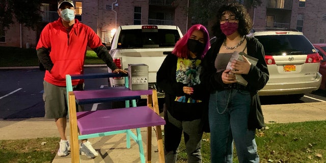 In this photo provided by Jessica Berrellez, her husband, Al Berrellez, left, and daughter Bella Berrellez, right, drop off free desks for Karla Mendez on Tuesday, Sept. 15, 2020, in Gaithersburg, Md.