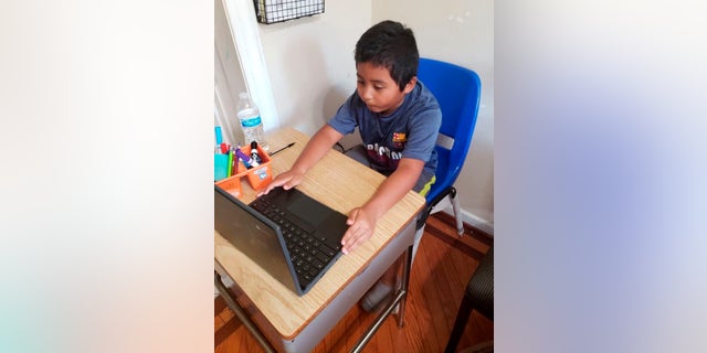 In this photo provided by Jessica Berrellez, student Jordan Dominguez Garcia attends a virtual class using his new desk, which was donated by the community, Thursday, Oct. 8, 2020, in Gaithersburg, Md.
