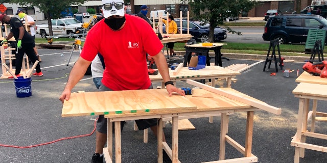 In this photo provided by Jessica Berrellez, her husband, Al Berrellez, builds a desk in Gaithersburg, Md., on Friday, Sept. 25, 2020. (Jessica Berrellez via AP